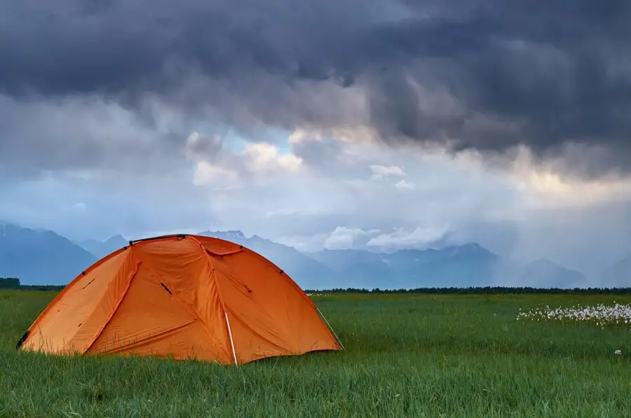 Camp during a thunderstorm with mountains on foreground